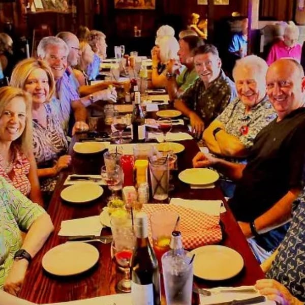 Smiling diners seated at a long table with drinks and empty plates at The Horny Toad.